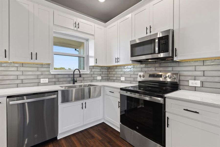 Kitchen with white cabinetry, sink, dark wood-type flooring, tasteful backsplash, and appliances with stainless steel finishes