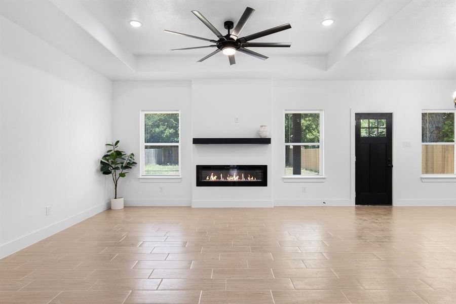 Unfurnished living room featuring ceiling fan and a tray ceiling