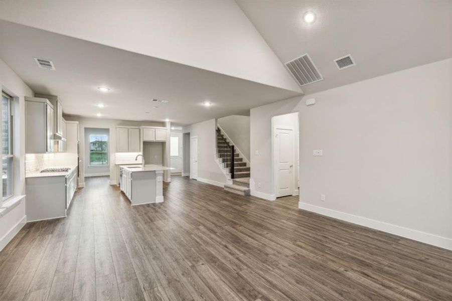 Unfurnished living room featuring dark hardwood / wood-style flooring, high vaulted ceiling, and sink