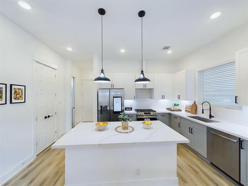 The kitchen offers quartz countertops, stainless steel appliances, recessed lighting, and shaker cabinets and hardware with under cabinet lighting.
