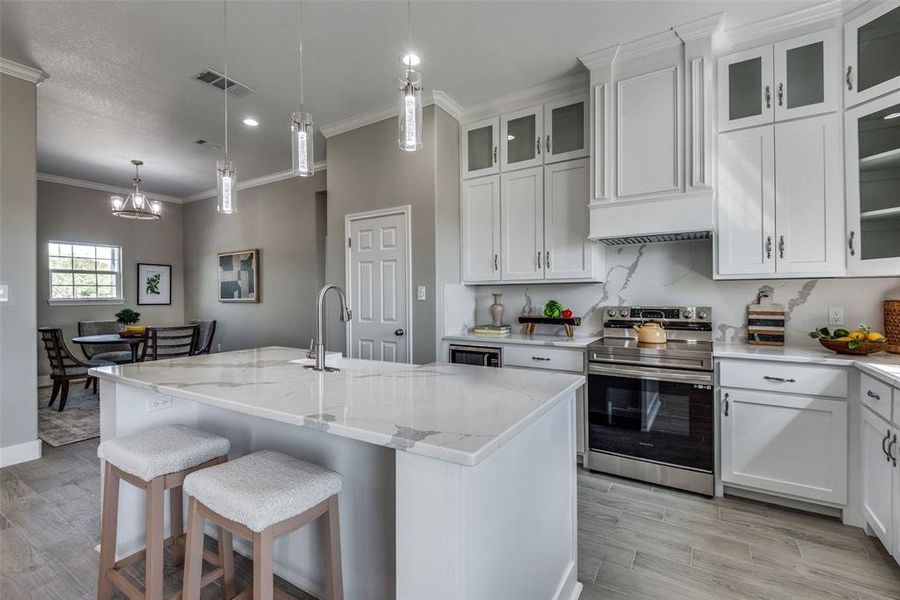 Kitchen with an island with sink, white cabinets, electric stove, and sink