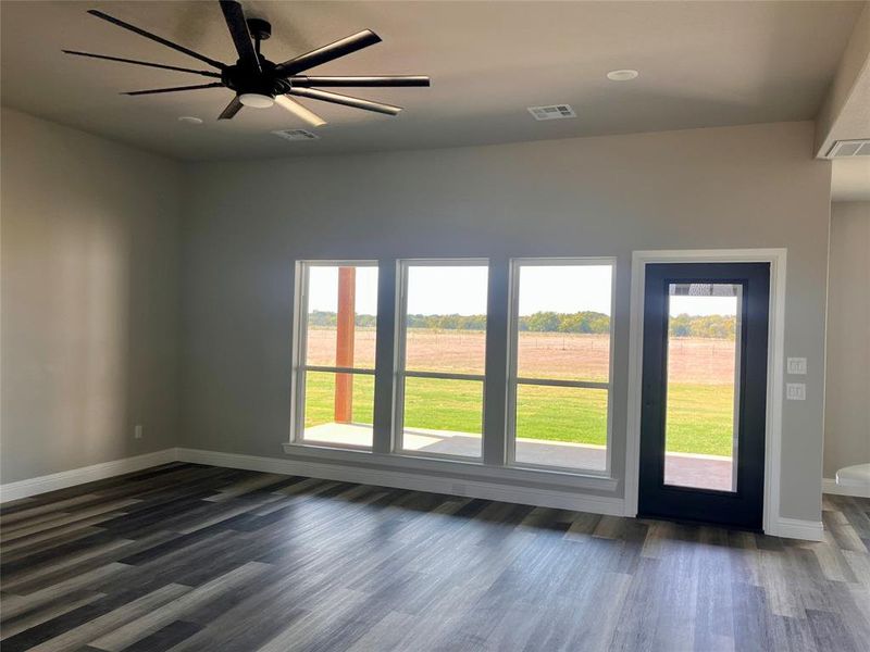 Unfurnished room featuring dark hardwood / wood-style floors, a wealth of natural light, and ceiling fan