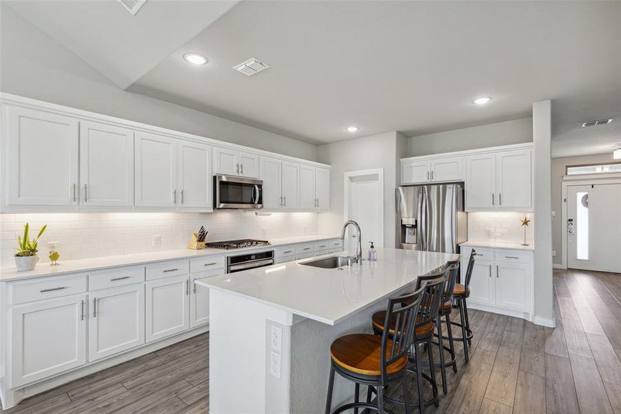 View of the kitchen with gas cooktop, stainless steel appliances, and door to pantry.