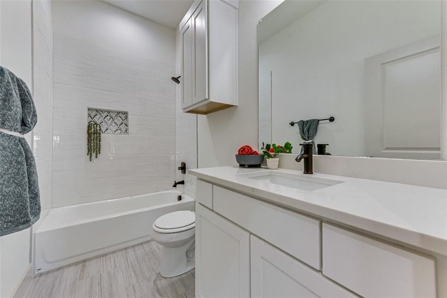 Full bathroom with tiled shower / bath, vanity, and toilet