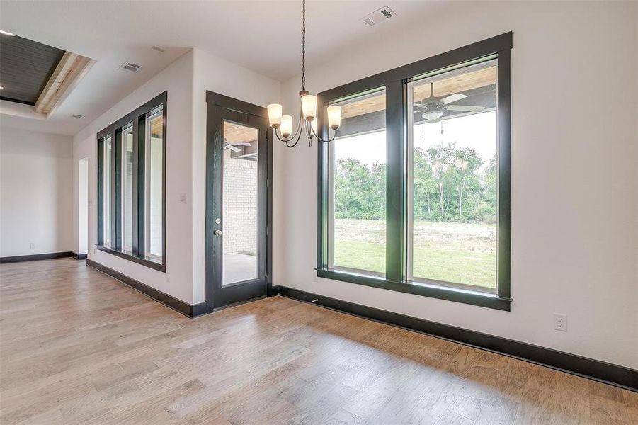 Unfurnished room featuring light hardwood / wood-style floors and ceiling fan with notable chandelier