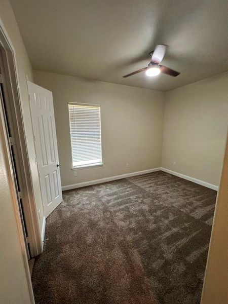 Carpeted empty room featuring ceiling fan