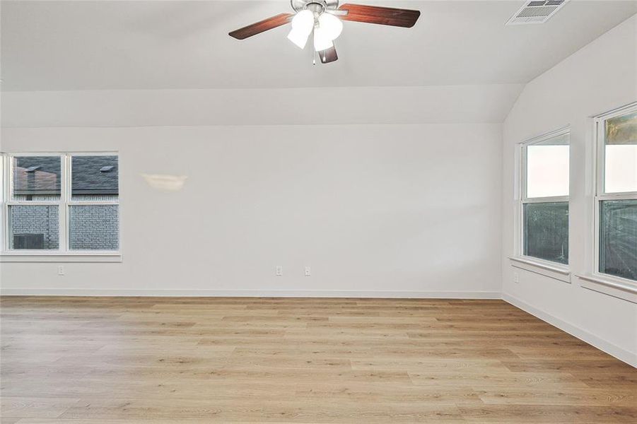 Unfurnished room with ceiling fan, light wood-type flooring, and vaulted ceiling