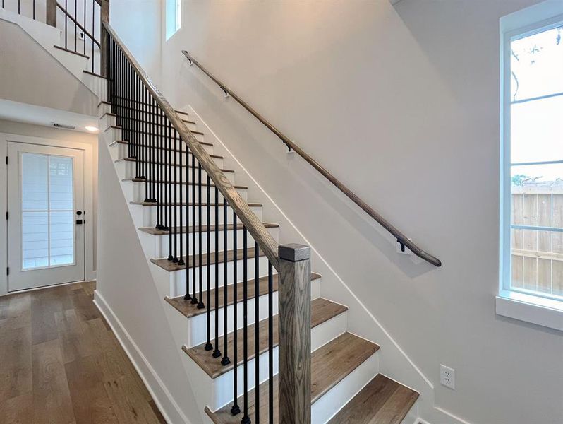 Elegant floating staircase with modern iron balusters and warm wood accents, enhancing the home's open and airy feel.