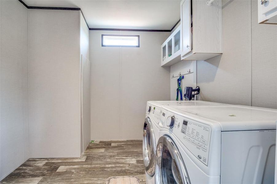 Washroom featuring crown molding, separate washer and dryer, dark hardwood / wood-style flooring, and cabinets