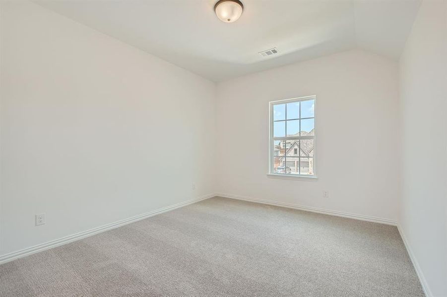 Spare room featuring carpet flooring and lofted ceiling