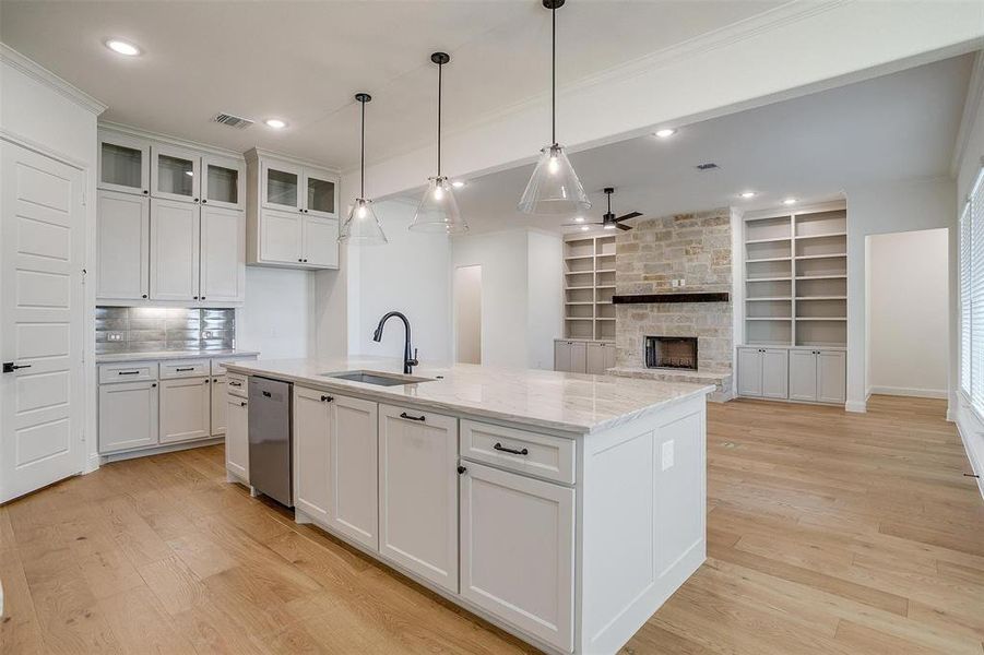Kitchen with built in features, white cabinets, sink, a fireplace, and light stone counters