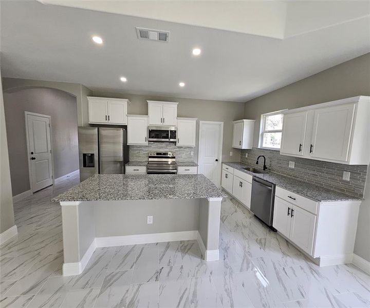 Kitchen featuring white cabinets, a kitchen island, stainless steel appliances, and sink