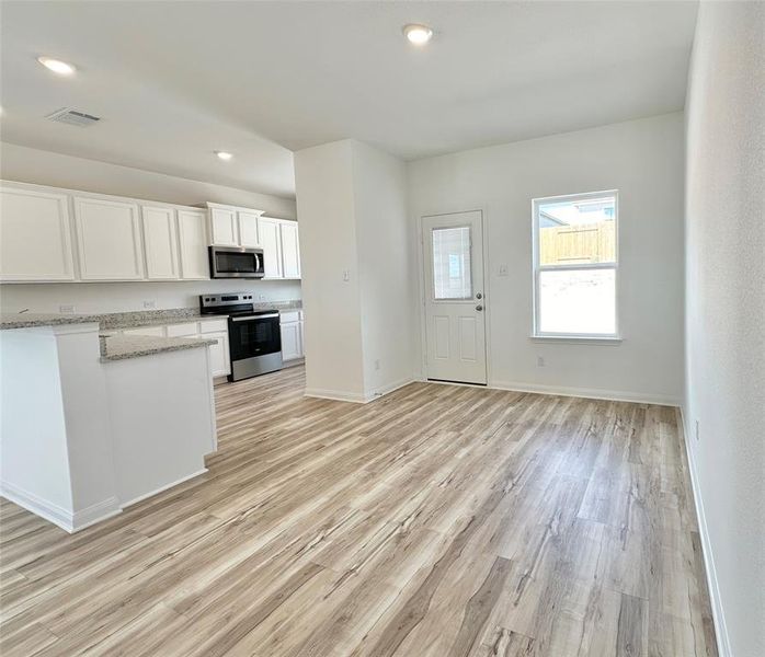 Kitchen includes granite countertops, luxury vinyl plank flooring, 36” upper cabinets with crown molding, a full suite of stainless-steel Whirlpool appliances – including refrigerator with ice maker, recessed lighting, and a large single basin sink.