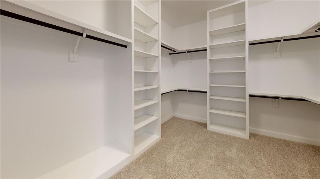 Step into the ROClake's primary bedroom closet, where elegance meets practicality. This expansive space features sleek, built-in shelving and ample hanging space, designed to keep your wardrobe organized and easily accessible. Image depicts similar product at another ROC Homes community.