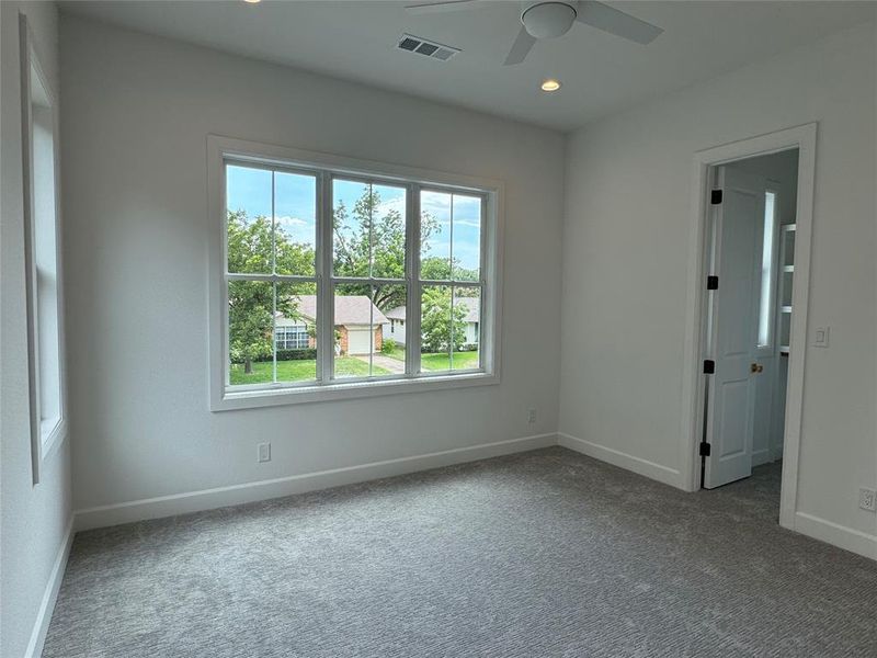 Spare room with ceiling fan, carpet flooring, and plenty of natural light