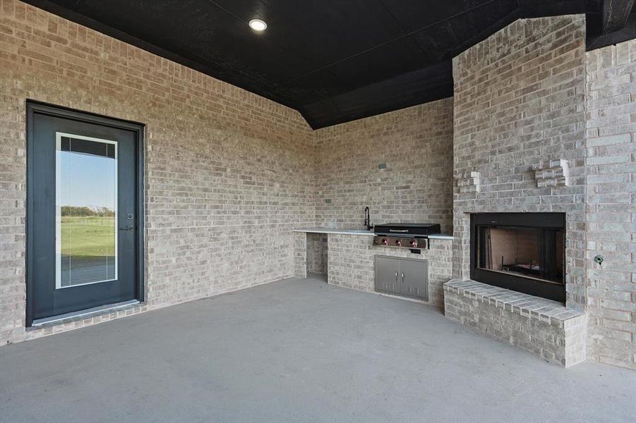 View of patio featuring an outdoor brick fireplace and grilling area