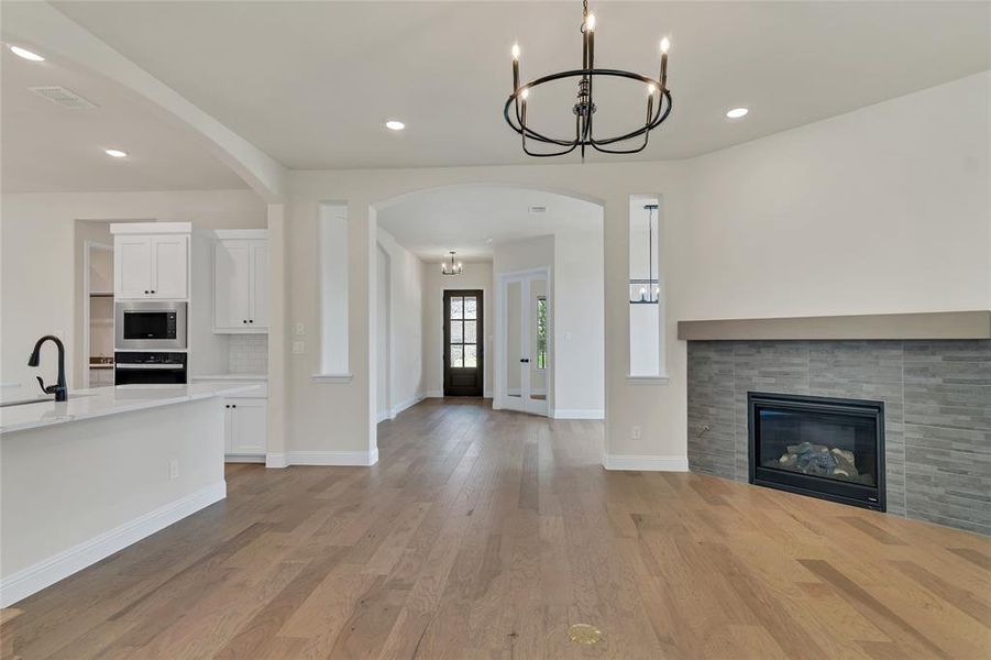 Unfurnished living room with sink, light hardwood / wood-style flooring, a fireplace, and a chandelier