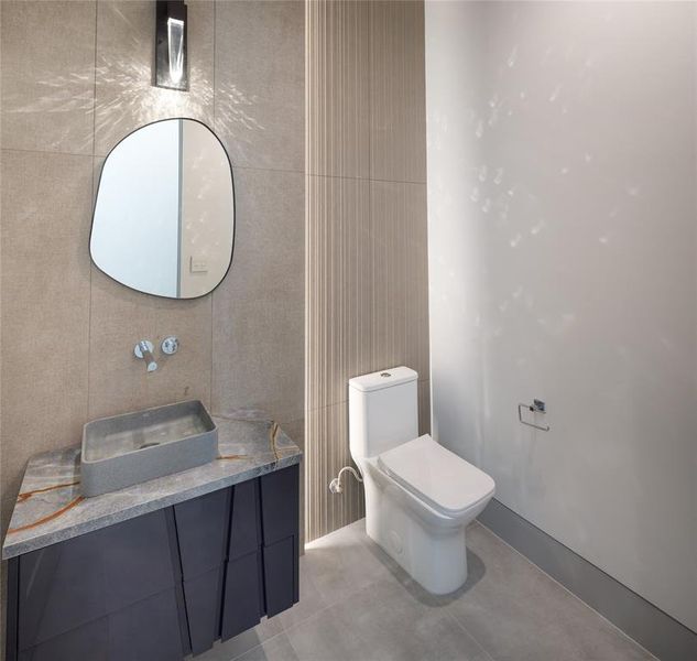 First floor powder room with custom-built furniture style vanity, porcelain backsplash, framed mirror and designer wall sconce