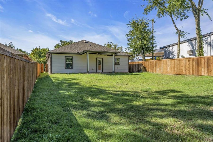 Rear view of property featuring ceiling fan and a lawn