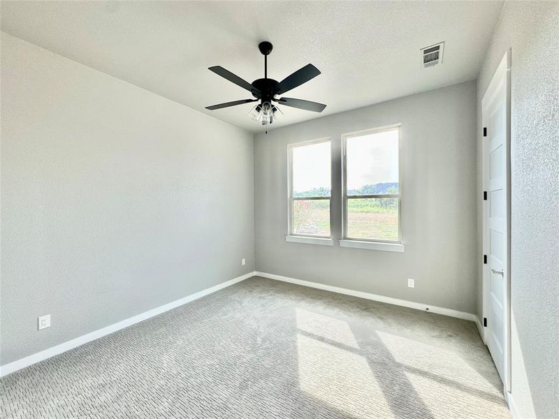 Carpeted secondary room with ceiling fan