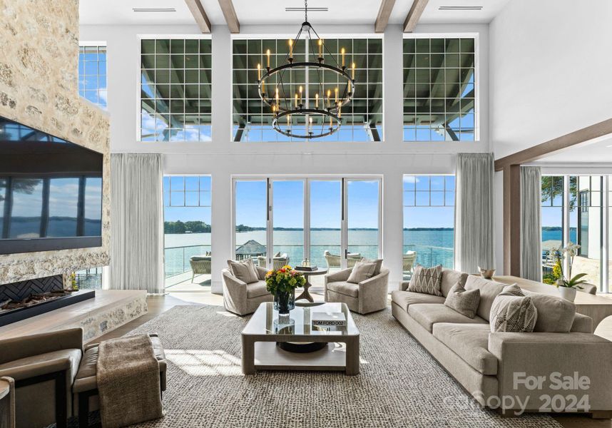 Two story Grand Salon featuring exposed wood beams & a window expanse that frames long range water views with fold away doors that lead to the terrace.