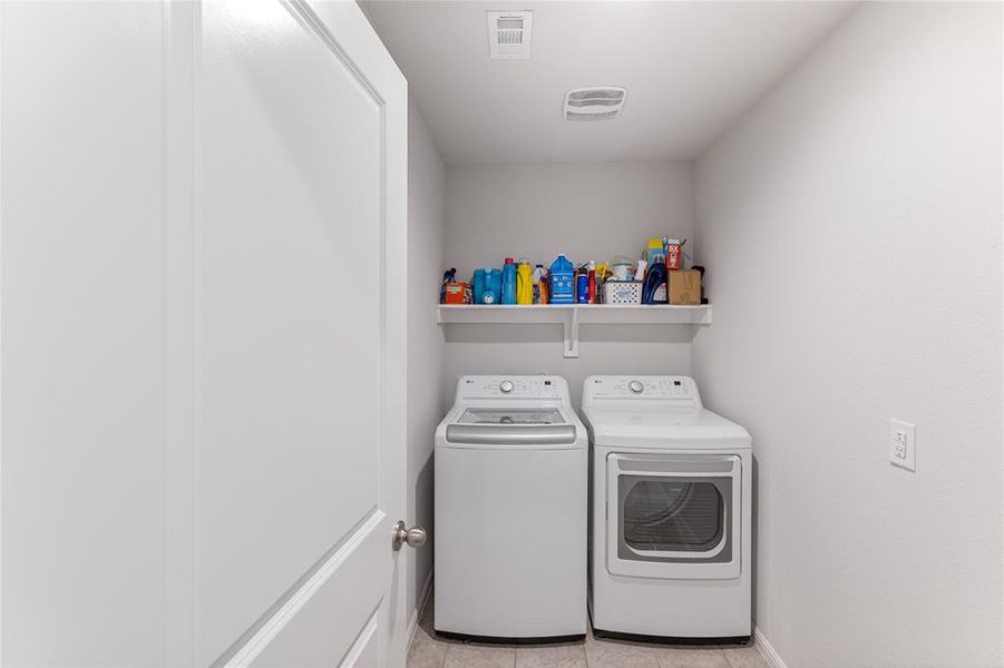 Washroom with light tile patterned flooring and independent washer and dryer