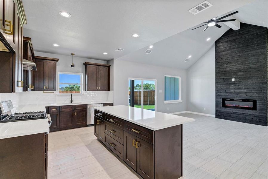 Kitchen featuring decorative light fixtures, lofted ceiling with beams, stainless steel dishwasher, and a healthy amount of sunlight