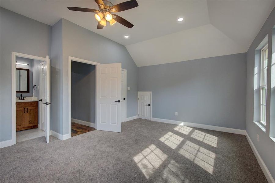 Bedroom 3 with lofted ceiling, ensuite bath, ceiling fan, and light colored carpet