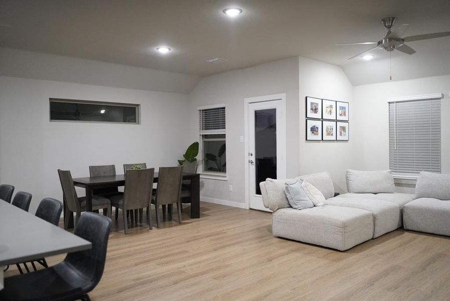 Living room with ceiling fan, vaulted ceiling, and light hardwood / wood-style flooring