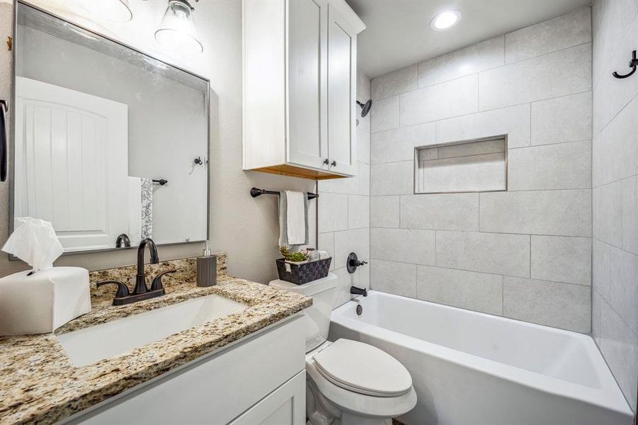 Full bathroom featuring vanity, tiled shower / bath, and toilet