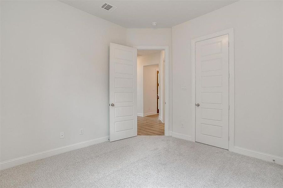 Unfurnished bedroom with light carpet and a closet