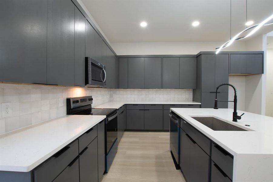 Kitchen featuring gray cabinets, sink, a kitchen island with sink, and appliances with stainless steel finishes