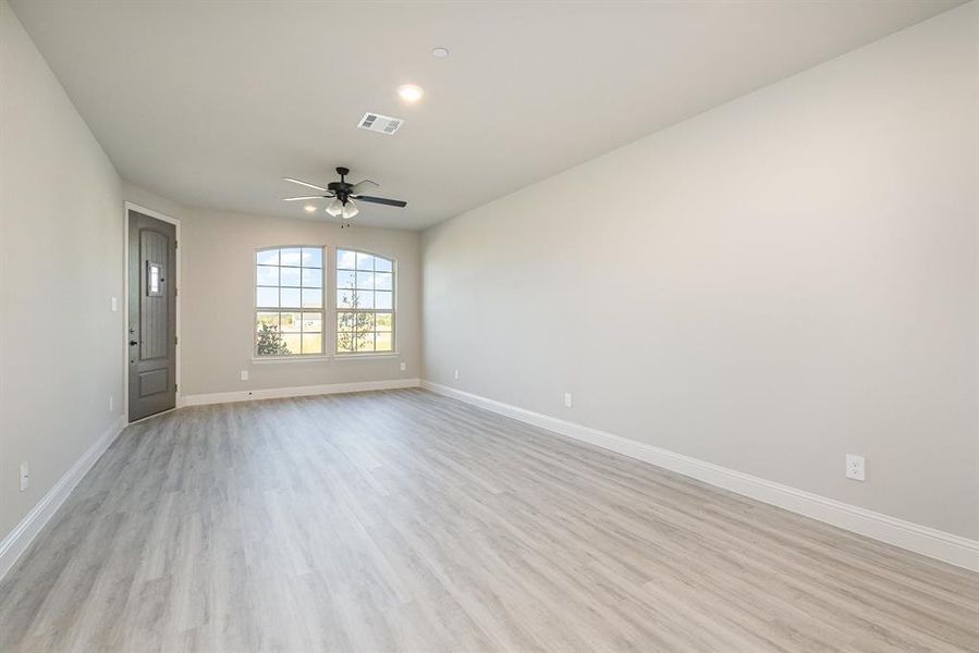 Empty room with light hardwood / wood-style floors and ceiling fan