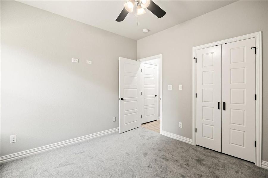 Secondary bedroom with light colored carpet, a closet, and ceiling fan