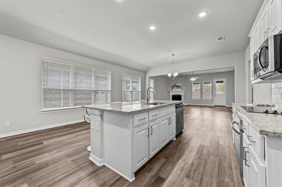 Kitchen featuring hardwood / wood-style flooring, a center island with sink, white cabinetry, and sink