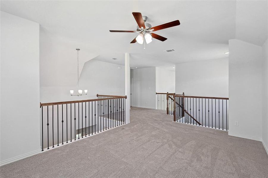 Spare room with ceiling fan with notable chandelier, vaulted ceiling, and light colored carpet