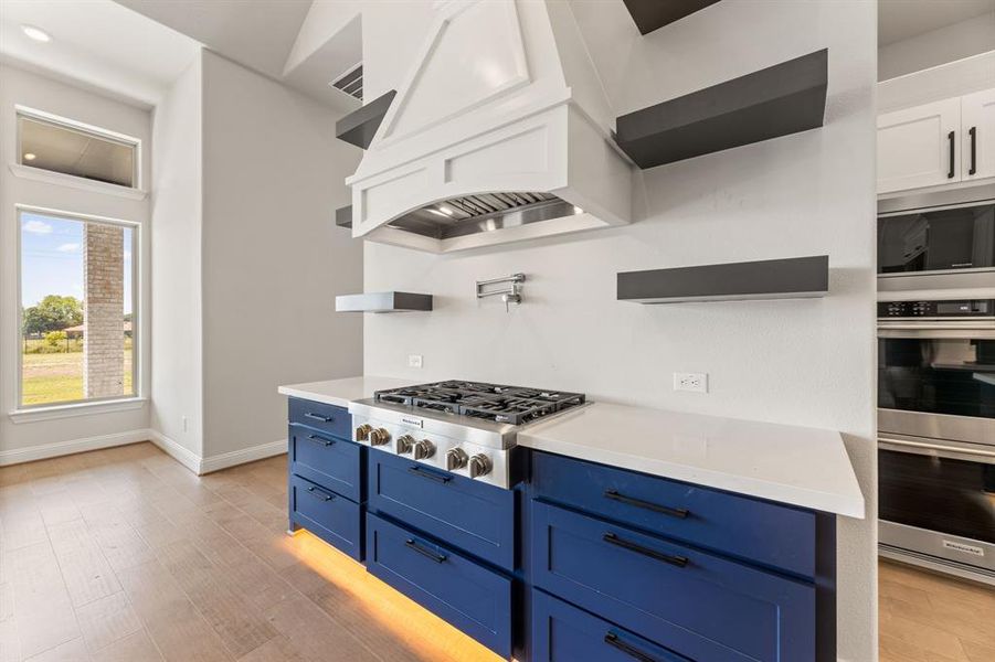 Kitchen featuring light hardwood / wood-style flooring, blue cabinetry, stainless steel appliances, and white cabinets