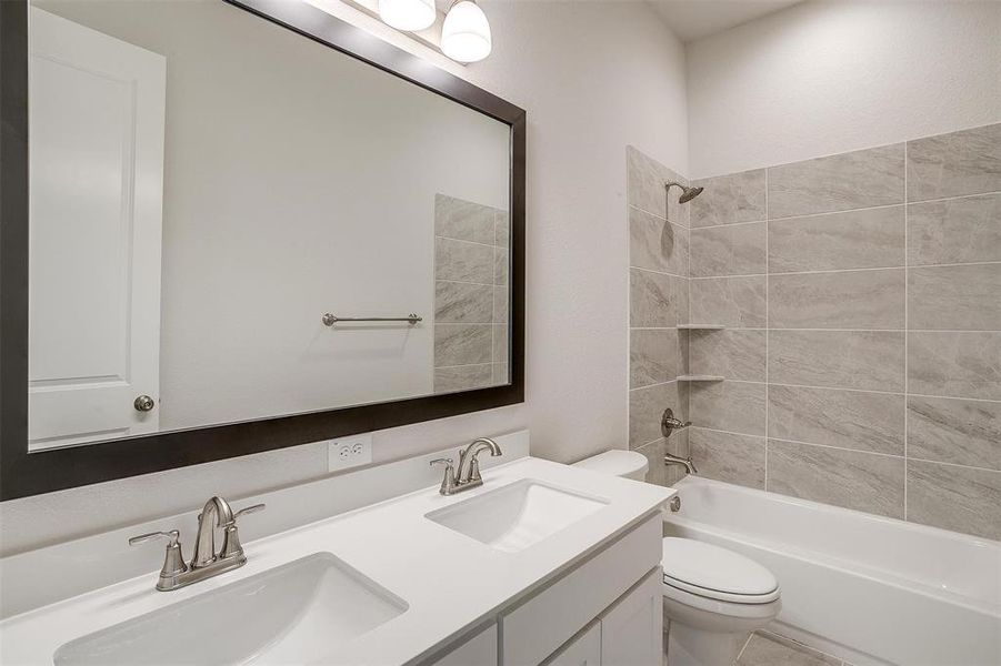 Full bathroom with tiled shower / bath combo, tile patterned flooring, toilet, and vanity