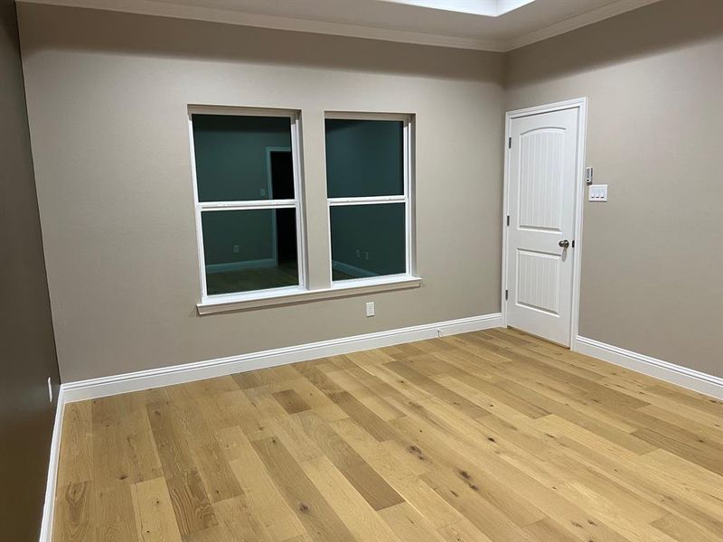 Empty room with ornamental molding and hardwood / wood-style floors