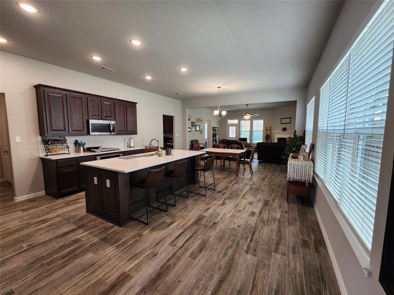 Kitchen featuring a kitchen island with sink, a breakfast bar area, dark brown cabinets, dark wood-type flooring.