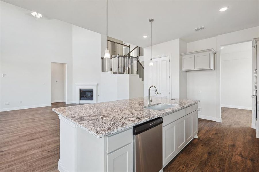 Kitchen featuring stainless steel dishwasher, sink, decorative light fixtures, and white cabinets