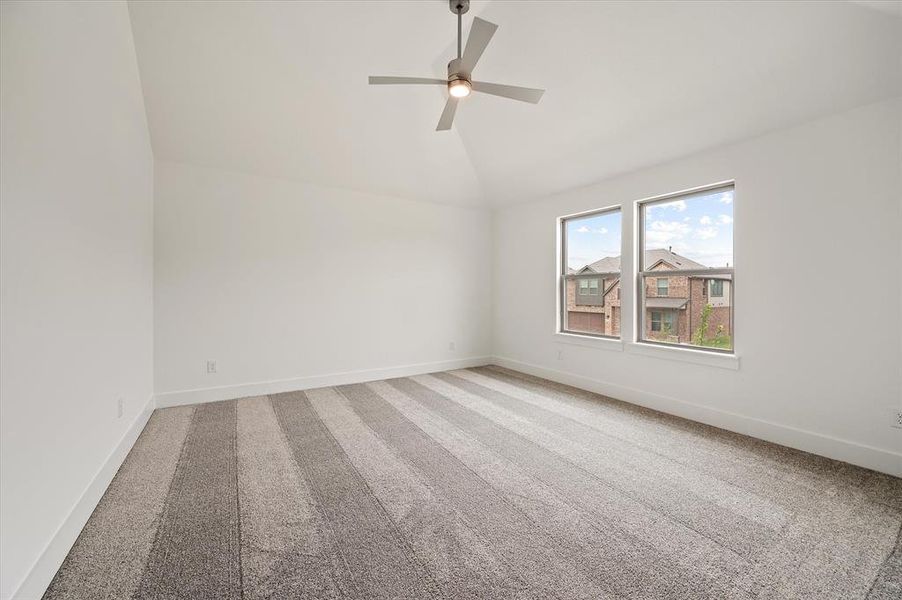 Carpeted spare room with vaulted ceiling and ceiling fan