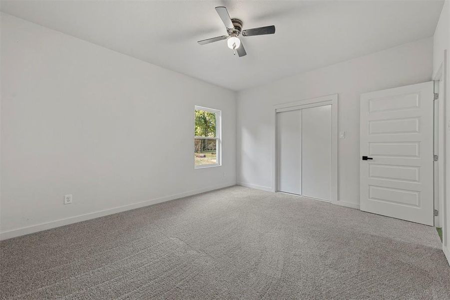 Carpeted spare room featuring ceiling fan