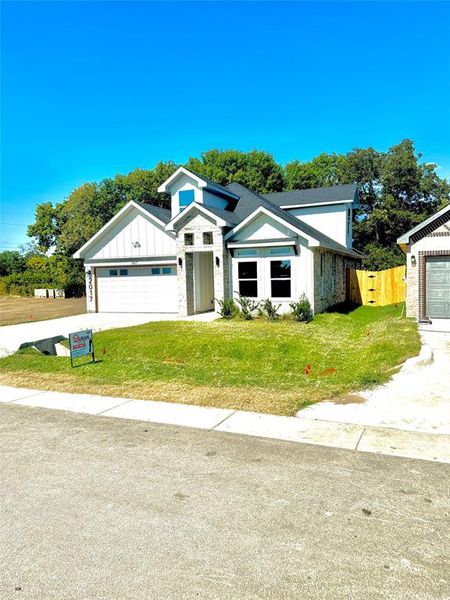 View of front facade featuring a front yard and a garage