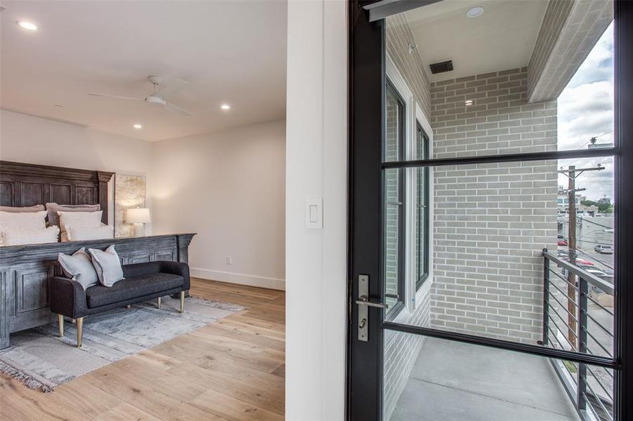 Bedroom with floor to ceiling windows, ceiling fan, light hardwood flooring, and brick wall