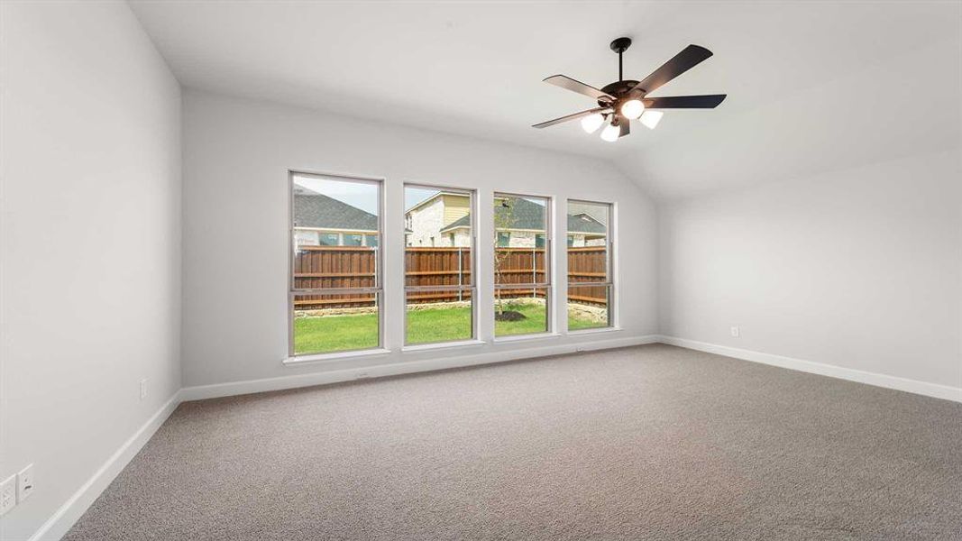 Spare room featuring carpet floors, ceiling fan, and vaulted ceiling