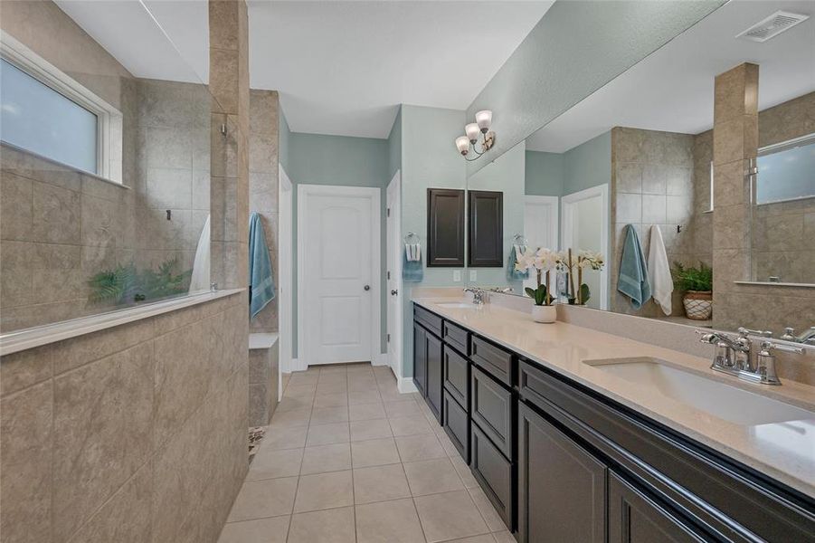 Primary ensuite features double sinks, large shower with pebble tile floor and built-in seat, water closet, linen closet and one of two walk-in closets.