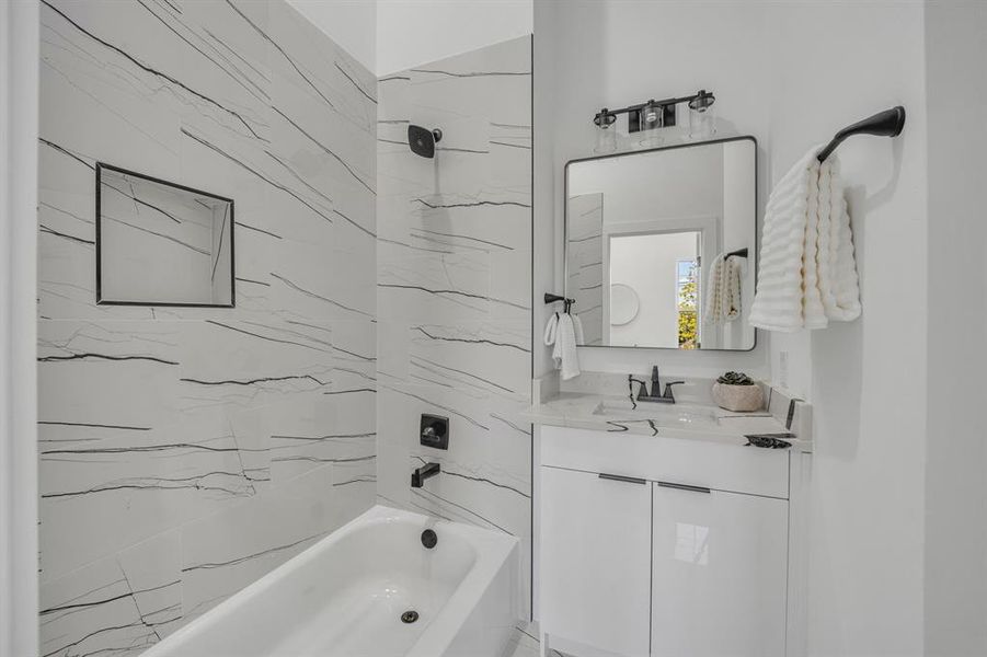 Bathroom with tiled shower / bath combo and vanity