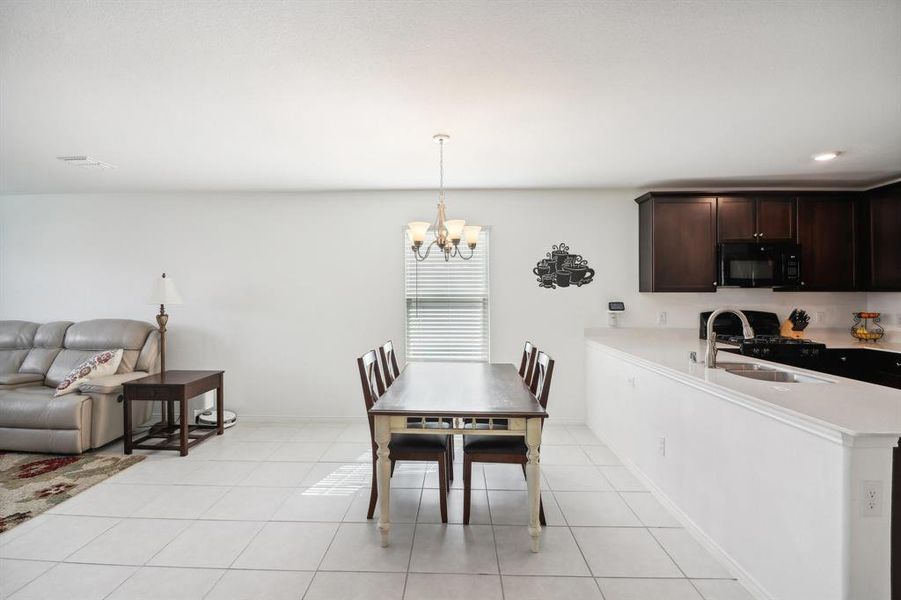 Dining room with light tile patterned flooring, sink, and an inviting chandelier