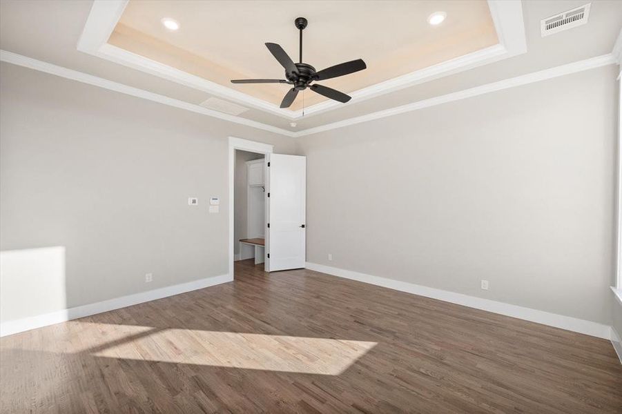 Spare room with crown molding, ceiling fan, a tray ceiling, and dark hardwood / wood-style flooring